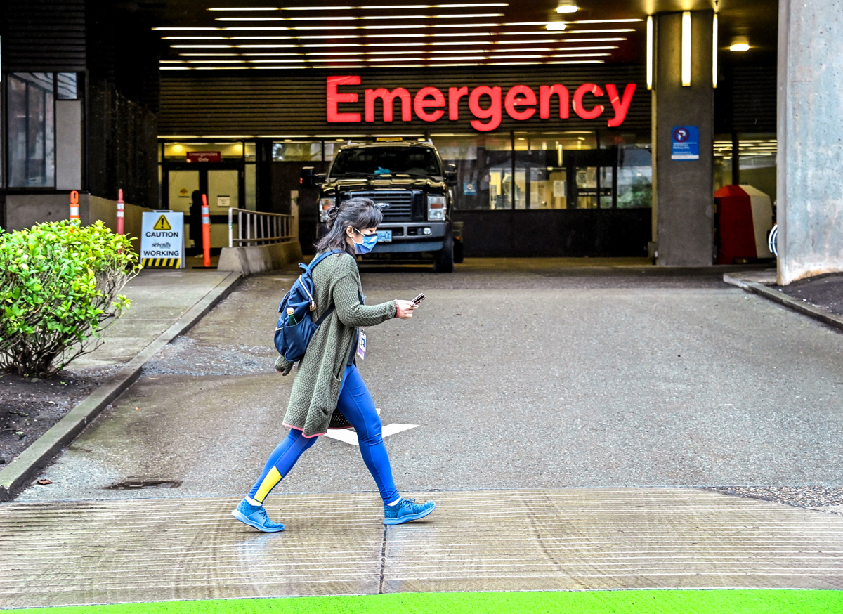 Masked person walks by hospital
