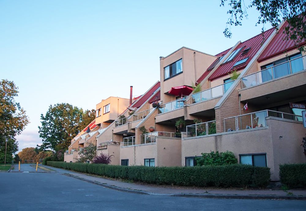 A row of connected beige housing units with red roofs.