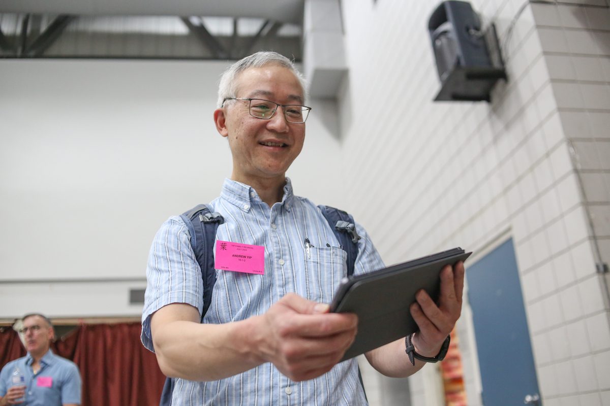 An ethnically Chinese man holds up a tablet in a gym.