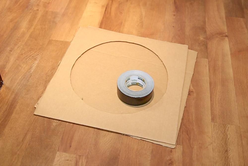 Two stacked photos depict supplies required for building Corsi-Rosenthal boxes. Top photo: a tabletop featuring measuring tape, a roll of green tape, scissors, a box cutter, a pencil and a Sharpie marker. Bottom photo: Two large pieces of cardboard are stacked together with circles cut out from the middle; a roll of silver duct tape rests on them.