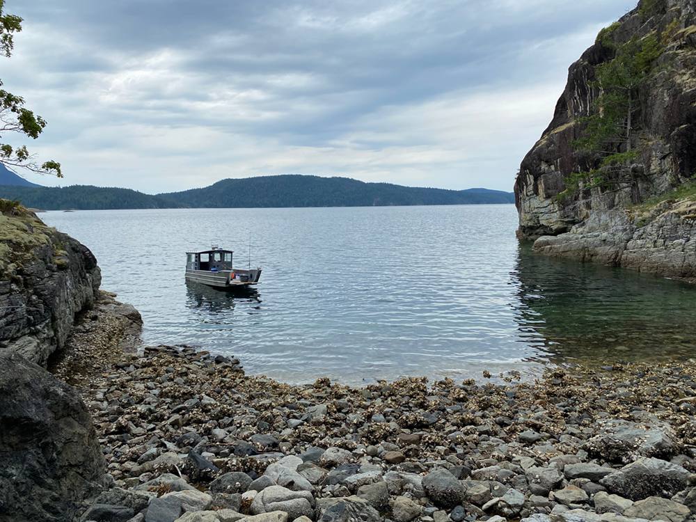 A silver landing craft waits off-shore in a rocky bay in Desolation Sound.