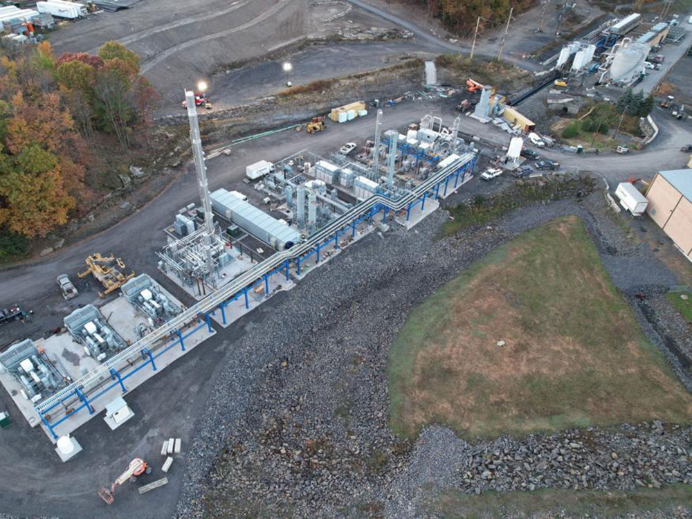 An aerial photograph shows the Keystone methane capture and RNG facility, with several different kinds of equipment and large silver-coloured silos. 