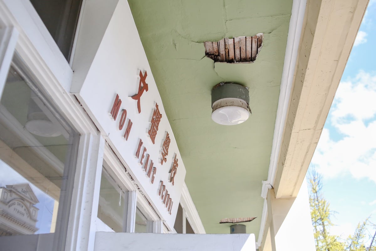A tea-green balcony ceiling reveals cracks and exposed wood.
