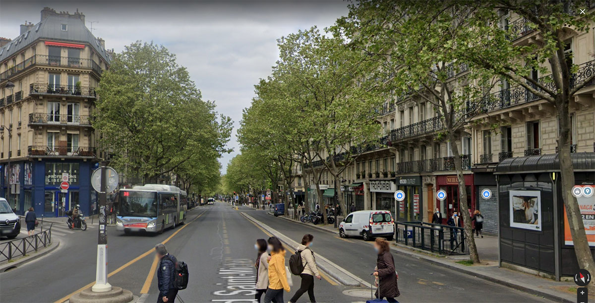 A corner in a Parisian neighbourhood where streets lined with six-storey neo-classical architectural buildings meet.