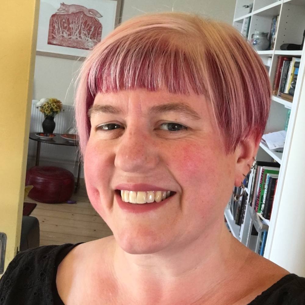 A woman with short salt and pepper hair  smiles at the camera.