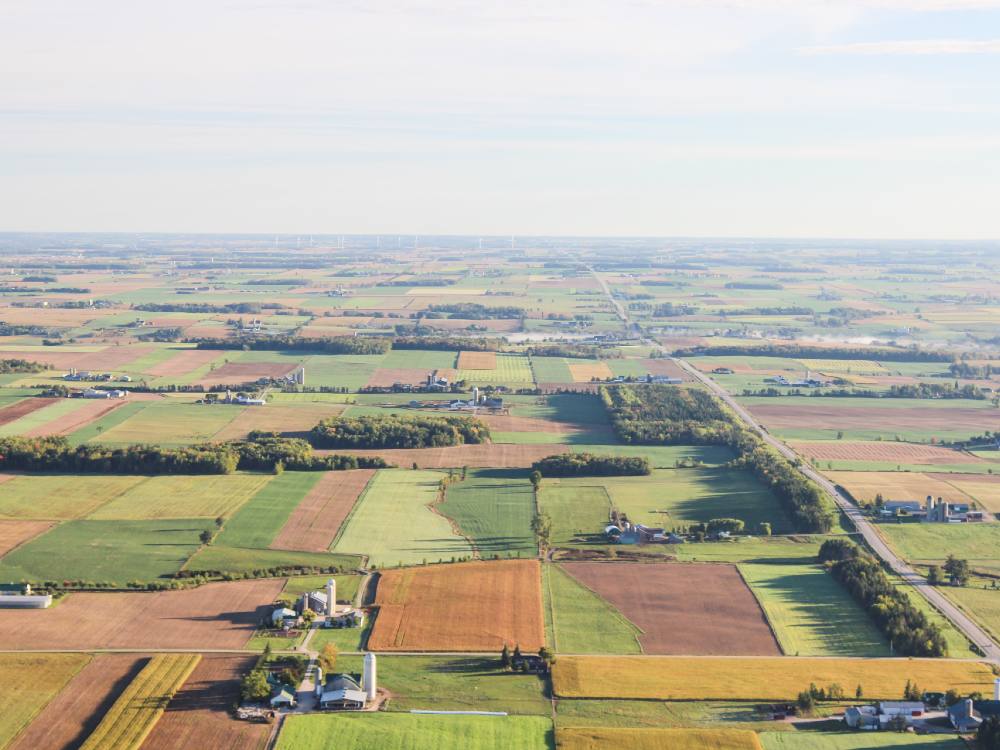 A patchwork of farmers' fields extends out into the horizon, with patches of crops in orange and green. 