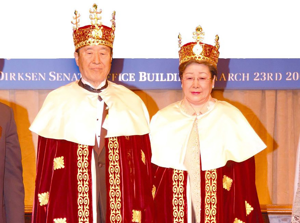 A Korean man and woman, late middle aged, stare straight ahead wearing robes and crowns.
