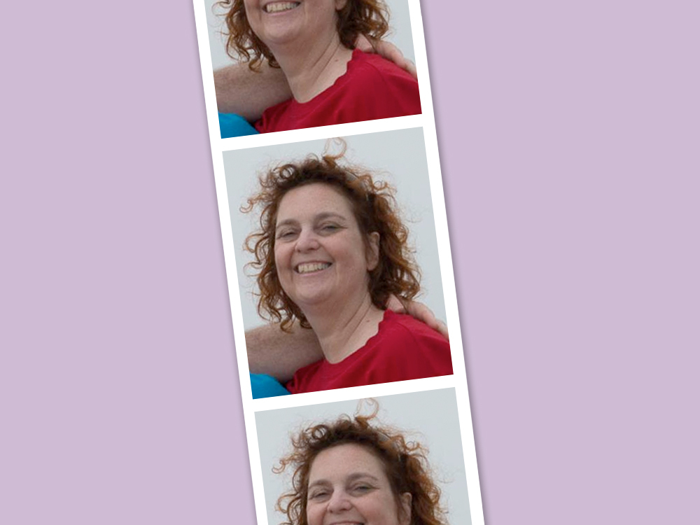 A small archival photo of a woman with brown curly hair, smiling widely. She is wearing a red shirt, and an unseen person’s arm is around her. The photo is styled across three duplicate images in the style of a piece of film strip. The image is set against a prismatic blue background.