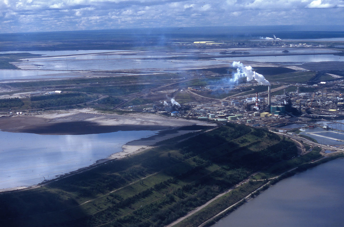 An aerial photo shows two large oilsands facilities, surrounded by giant tailing ponds.