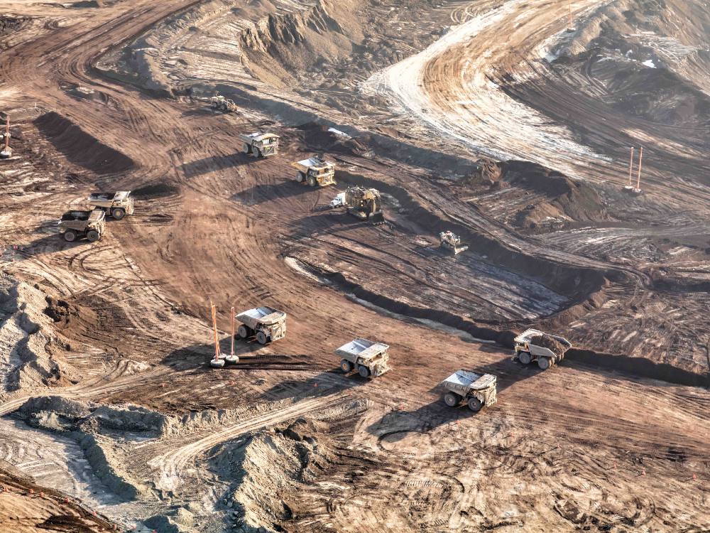 An aerials shot shows a large area of dirt with giant equipment rolling across it.