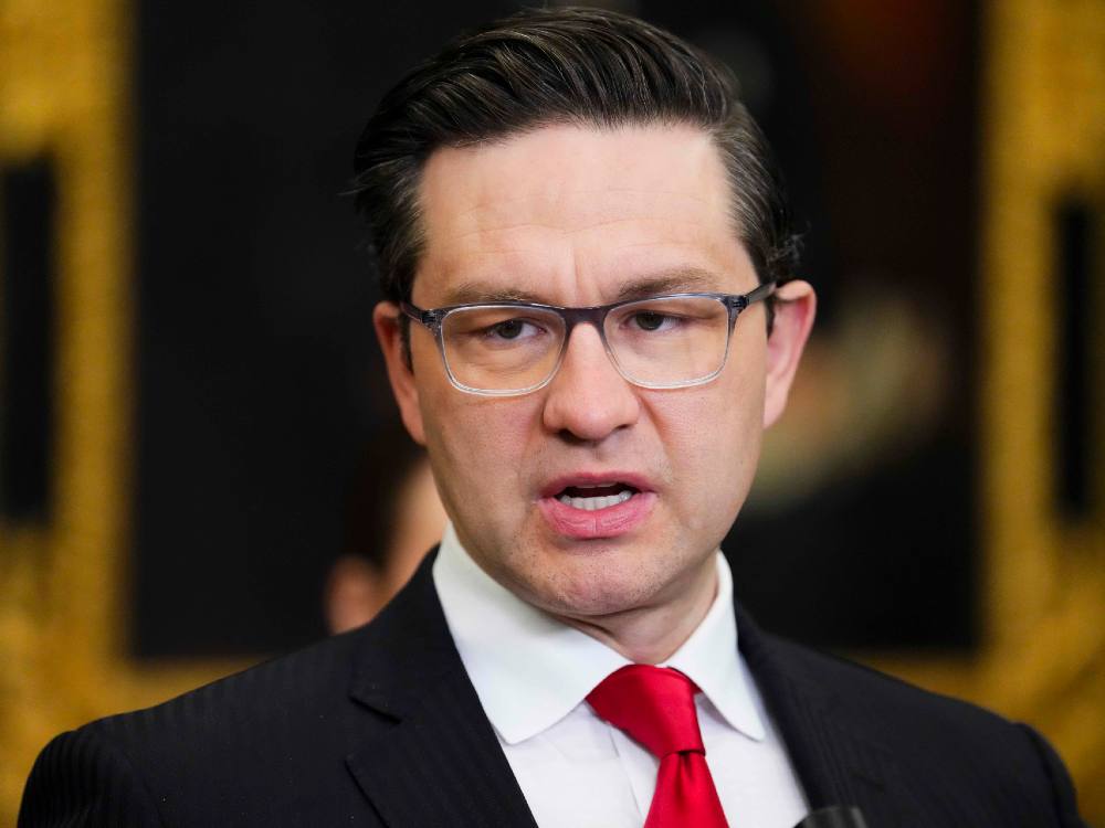 Pierre Poilievre wearing a dark suit, white shirt and red tie.
