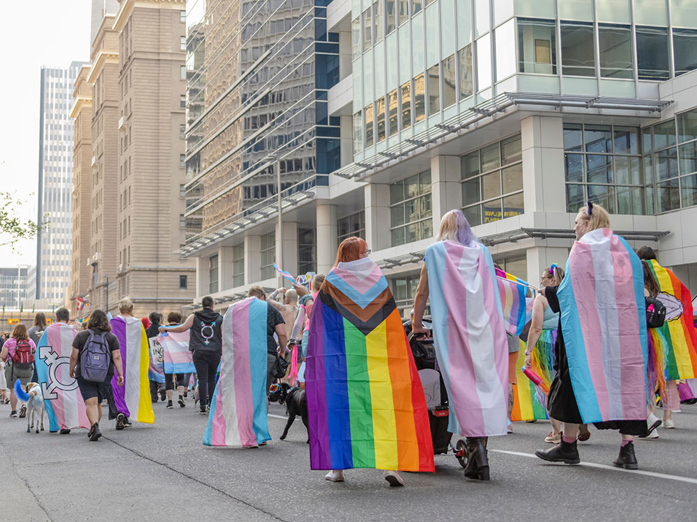 People walking with 2SLGBTQ+ flags during a pride parade in downtown Calgary on Sep. 4, 2022.