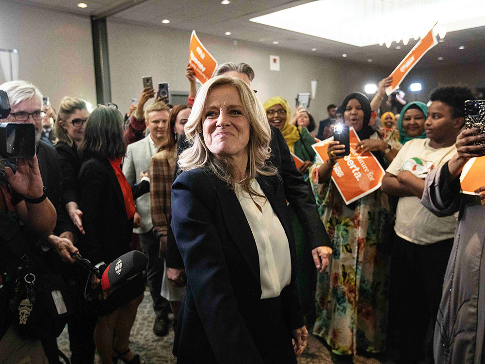 Rachel Notley looks past the camera, surrounded by supporters, come holding party signs, at the NDP’s election night event.