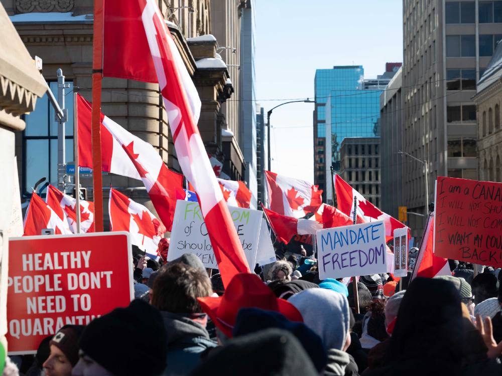 Protesters crowd an Ottawa street on January day carrying Canadian flags and signs saying “Healthy people don’t need to quarantine” and “Mandate Freedom.”