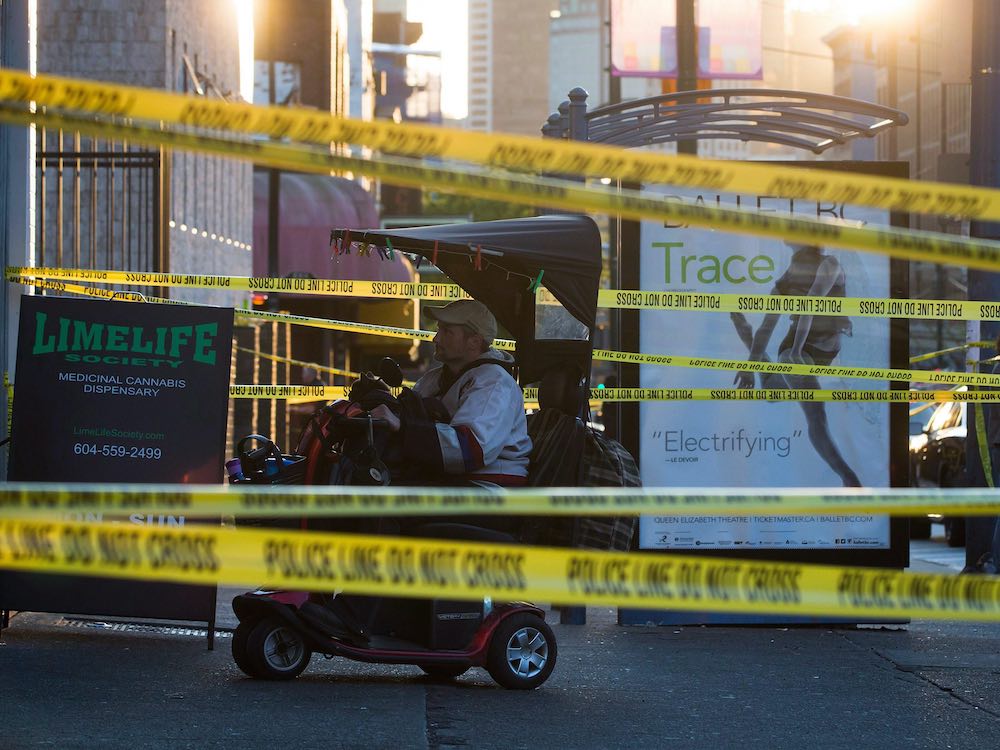 Yellow crime scene tape stretches across a Vancouver sidewalk.