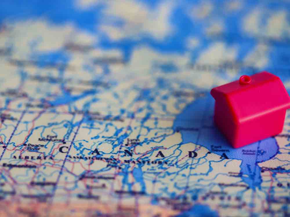 A small plastic home sits on a colour map of Canada.