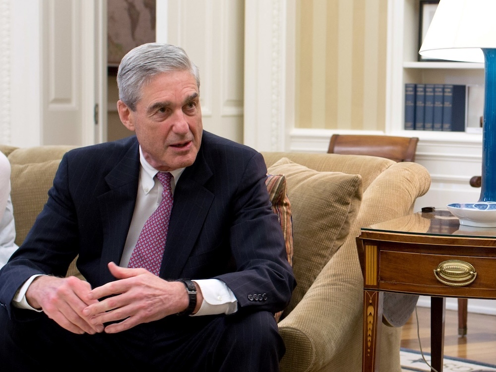 A late middle aged white man with thick, greying hair sits in an elegant couch in a well appointed office.