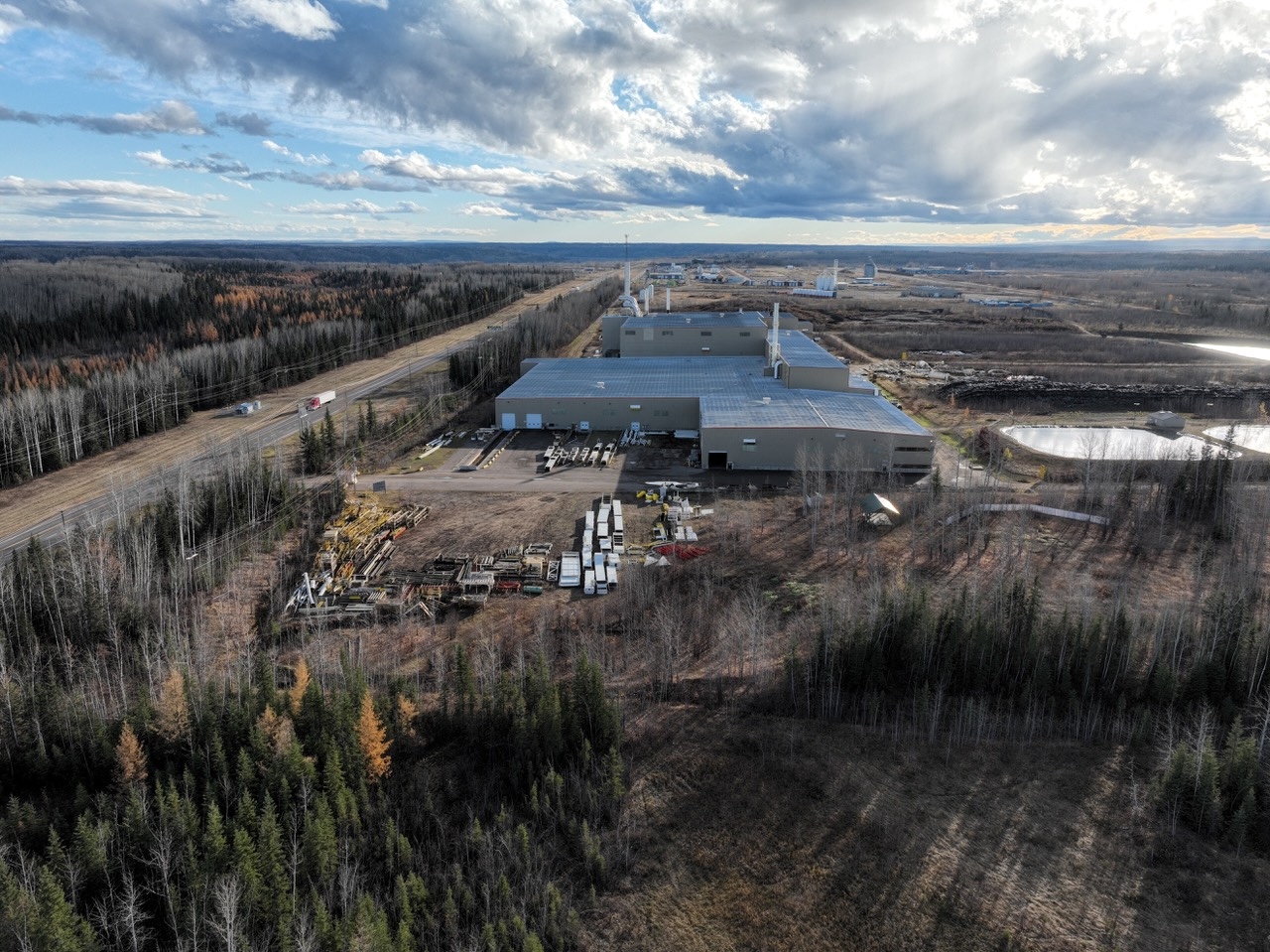 Two large industrial buildings are located in clearings in a forest.