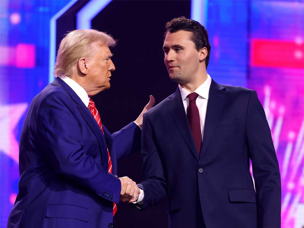 Donald Trump, left, shakes the hand of Charlie Kirk, right. Both are wearing suits and ties.