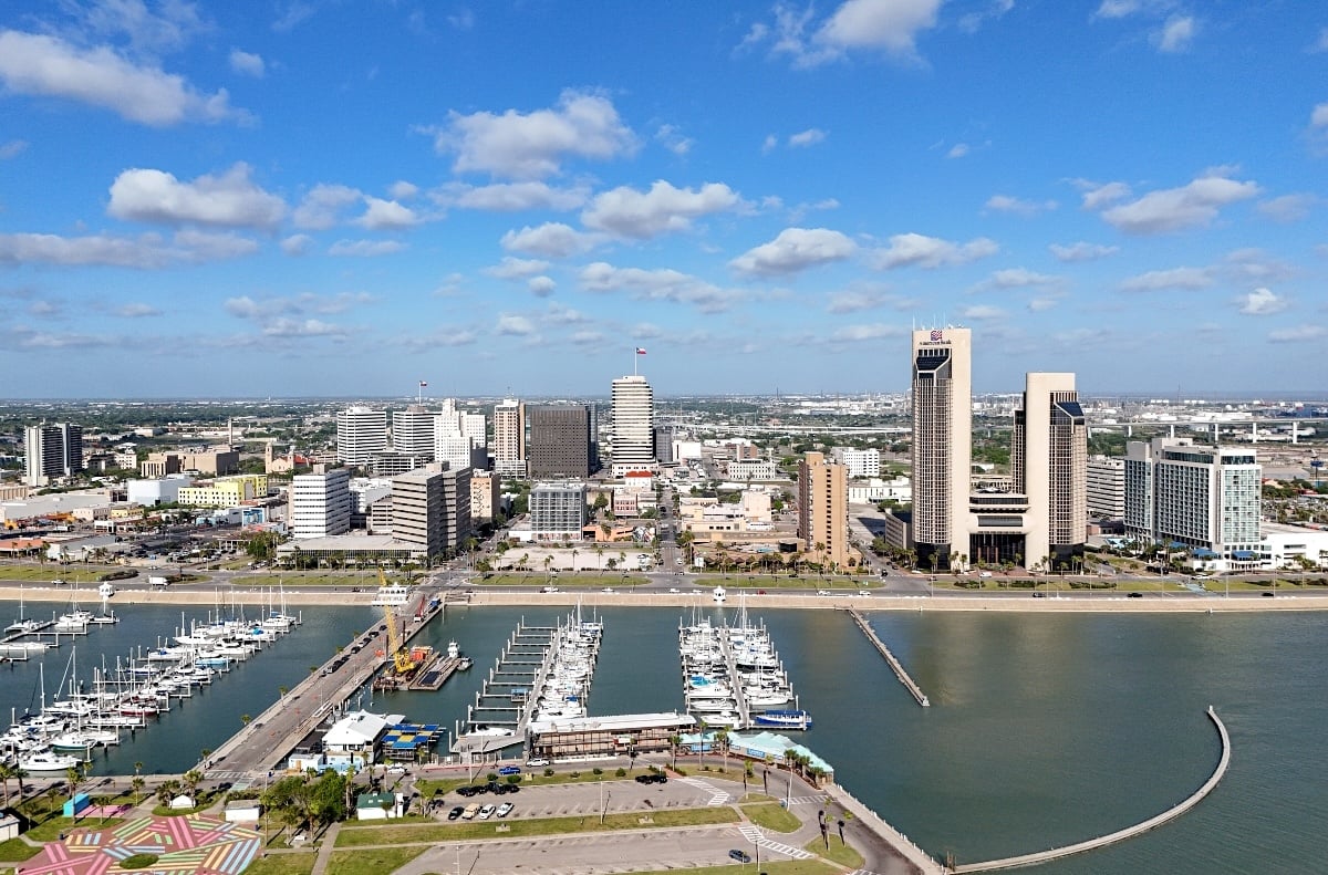 An aerial shot of Corpus Christi, Texas, shows a modest skyline in the centre of the photo with a marina and bridge in the foreground.