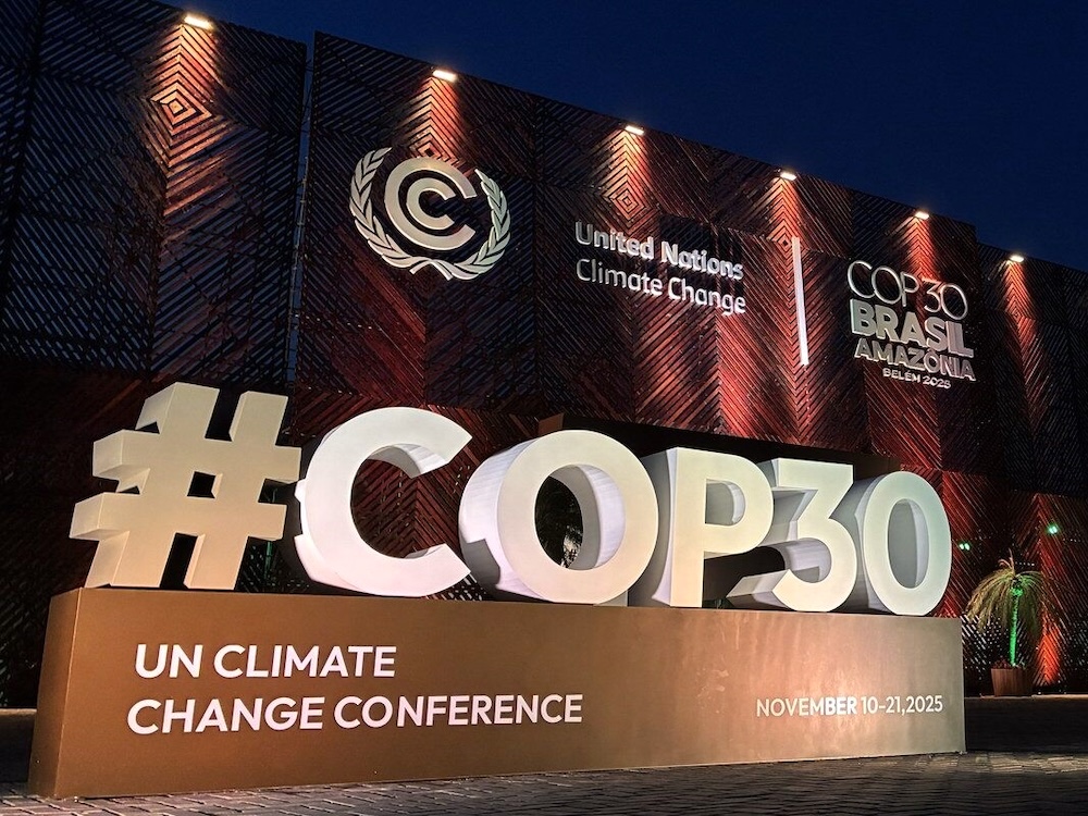 A large outdoor sign reads, &lsquo;#COP30 UN Climate Change Conference,&rsquo; lit up at night.