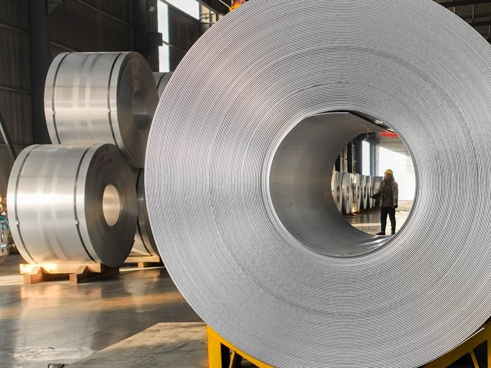 Giant rolls of pressed aluminum are stacked in a warehouse.
