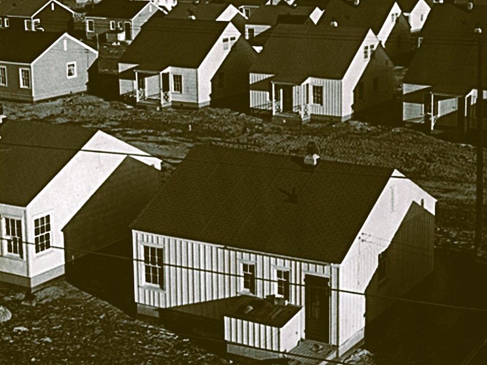 A black and white archival photo of several similar-looking homes built close together.