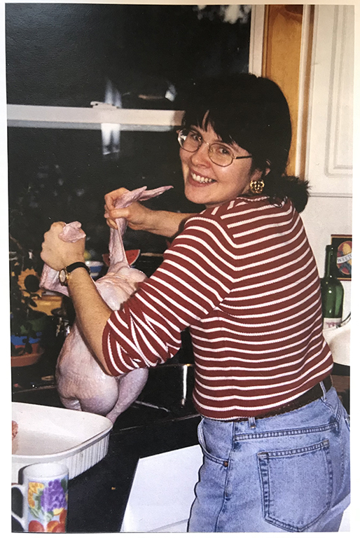Michelle Gamage’s aunt Diana holds a raw turkey over the sink in a photo that appears to have been taken in the late 1990s. She is smiling and looking back at the camera.