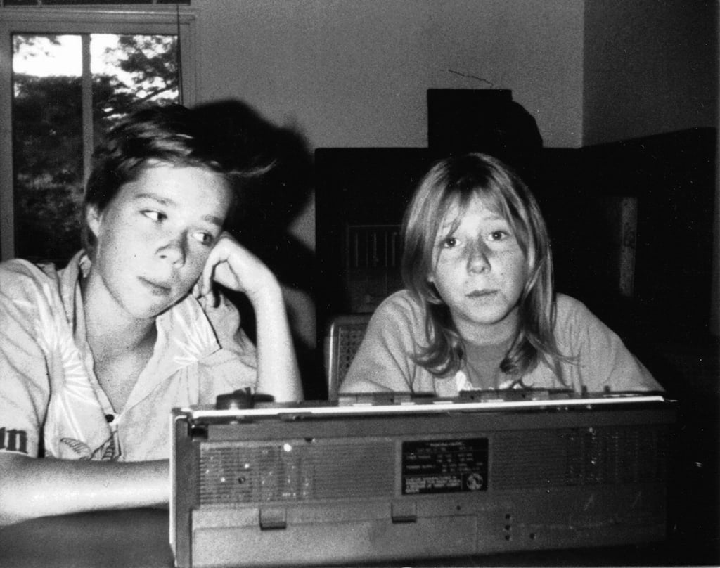 A black and white photograph depicts two children seated at a table behind a boombox stereo. Martha Wainwright, left, is the older sibling resting her hand on her chin while she looks at her little brother Rufus Wainwright, right, who is looking blankly at the camera.