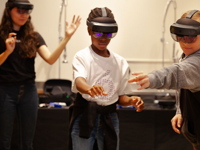 Three youth wear virtual reality headsets.