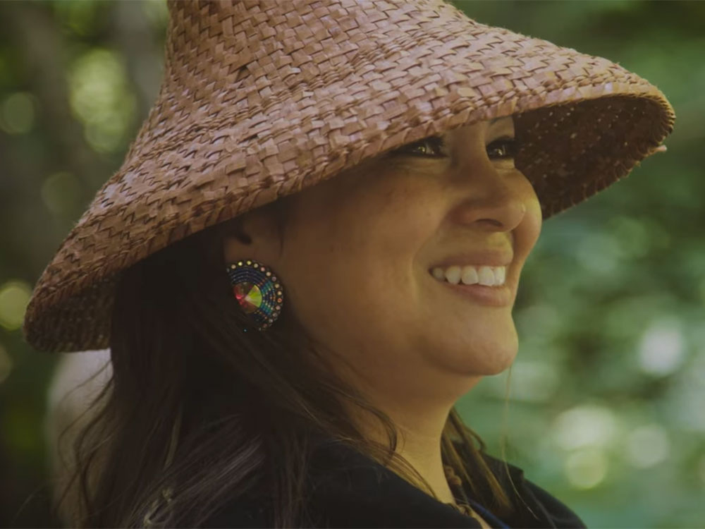 A person is smiling and wearing a cedar hat.