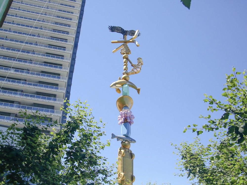 A tall, pastel coloured art installation stands against a bright blue sky. The work, by local artist Douglas Coupland, is titled Charm Bracelet and brings together ephemera that are said to represent the interplay between Burnaby’s culture and its retail and civic spaces.