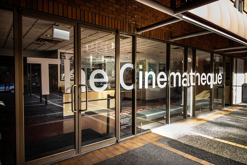 The front entrance of the Cinematheque features brown brick, glass doors, and the theatre’s name in bold white sans-serif typeface.