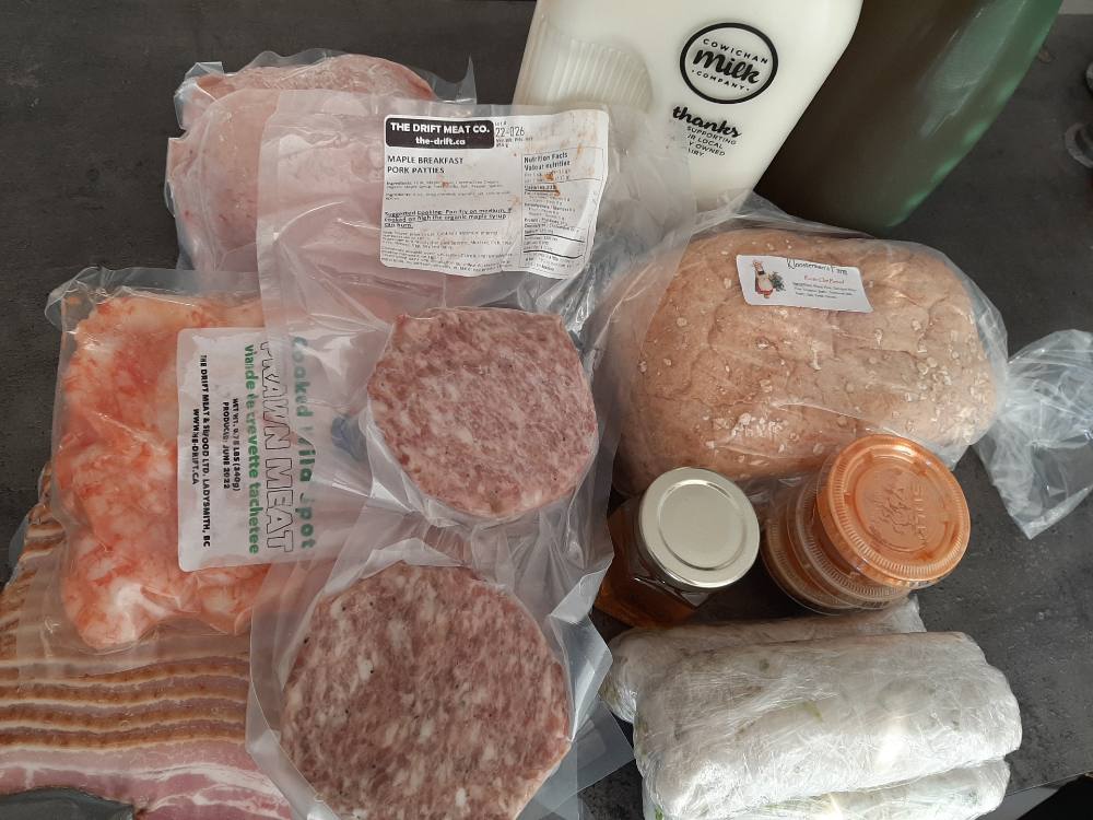 A bird’s-eye view of a selection of groceries from the author’s trip to the Cowichan Valley, including meats, milk and bread.