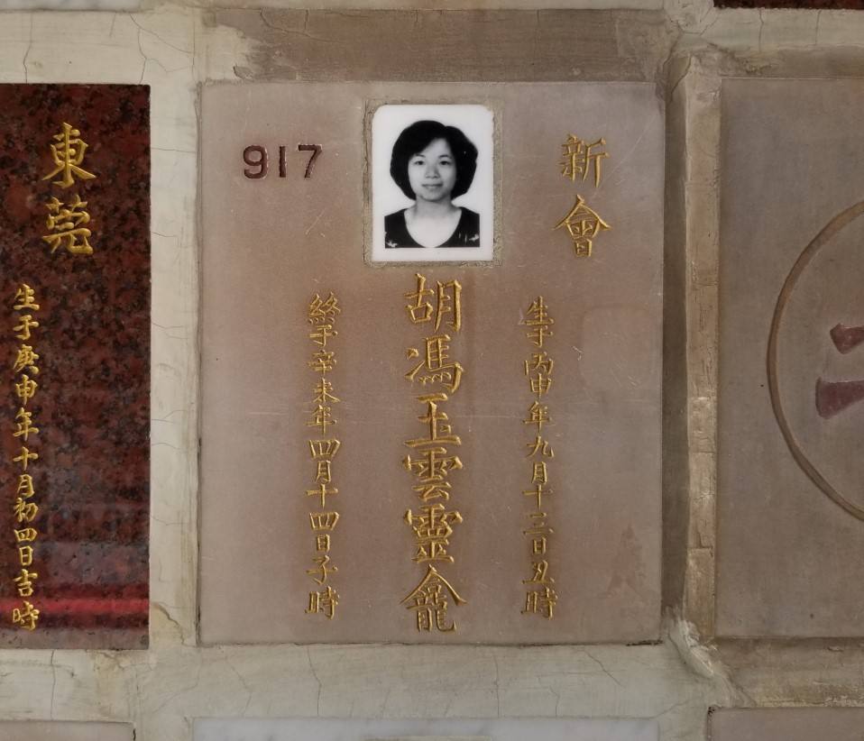 A light-coloured stone columbarium plaque that features a photo of the author’s aunt, Cloud.