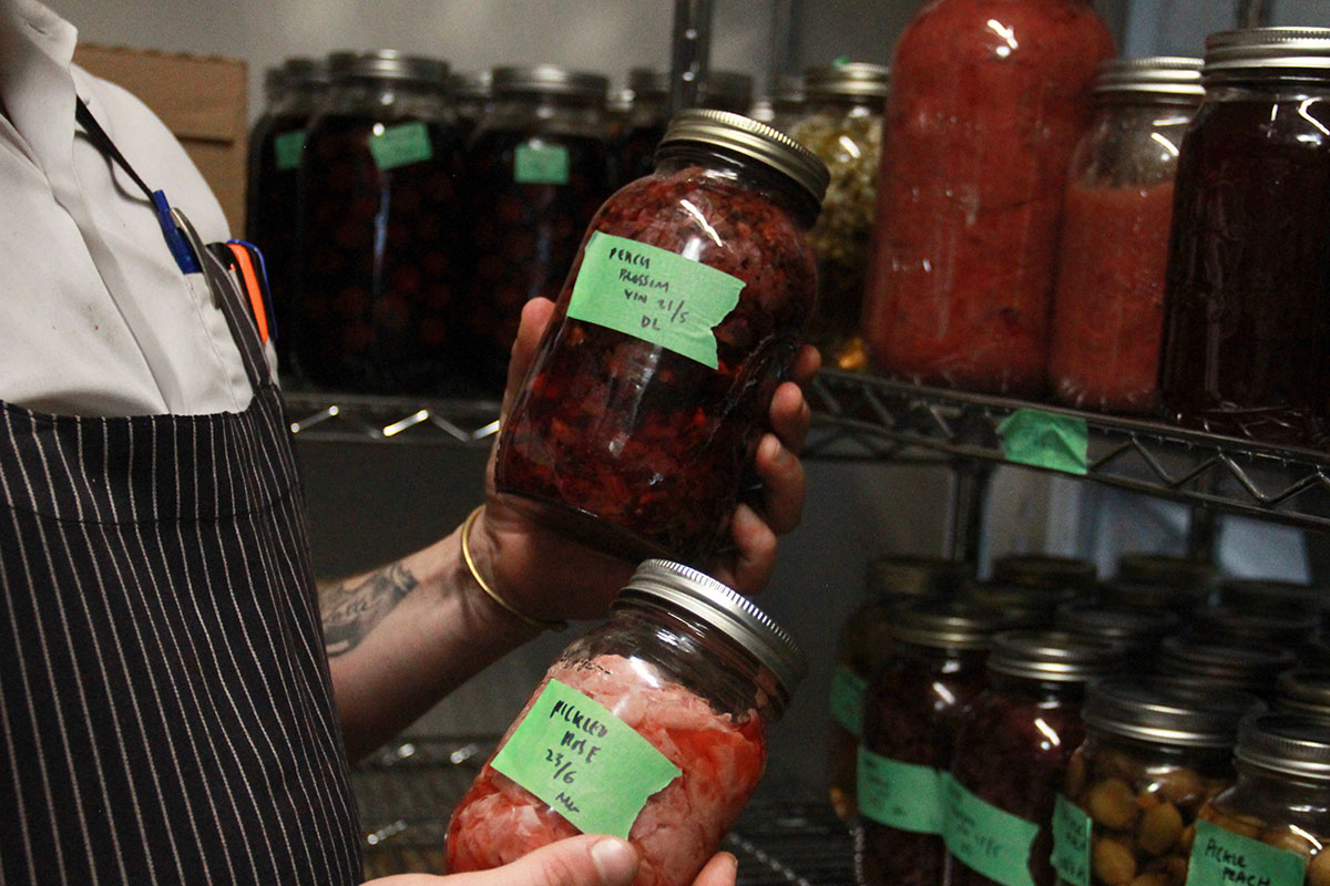 A man holds jars of flower preserves in mason jars.