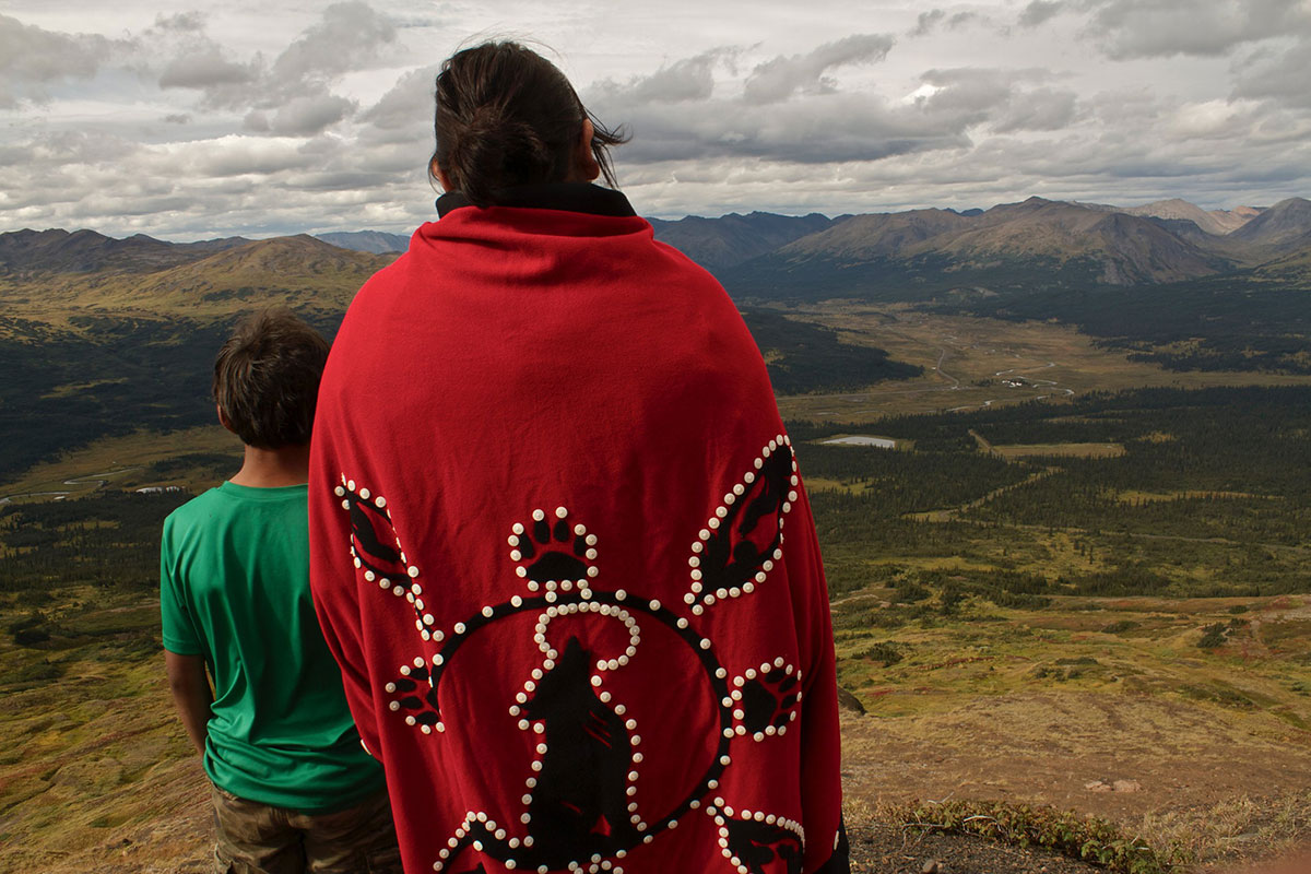 Rhoda Quock, right, is wearing a red ceremonial blanket while overlooking the river valley that comprises her homeland in northern B.C. Beside her in a green t-shirt is her son Caden.