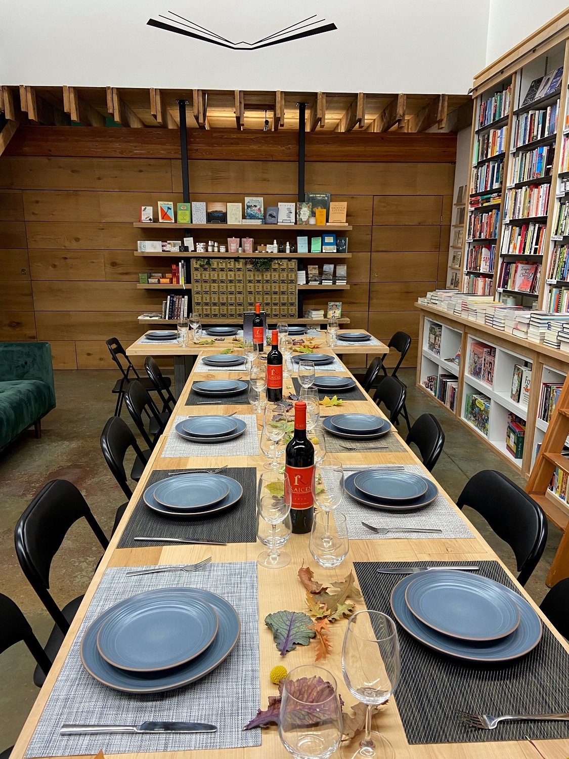 A long table with place settings inside a bookstore with a high ceiling.