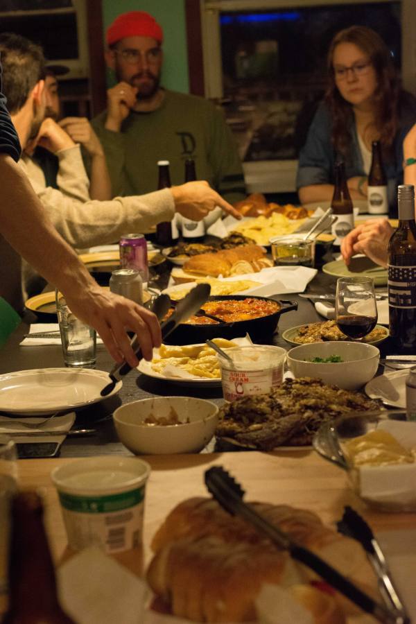 People are gathered around a long table filled with plates and dishes full of food.