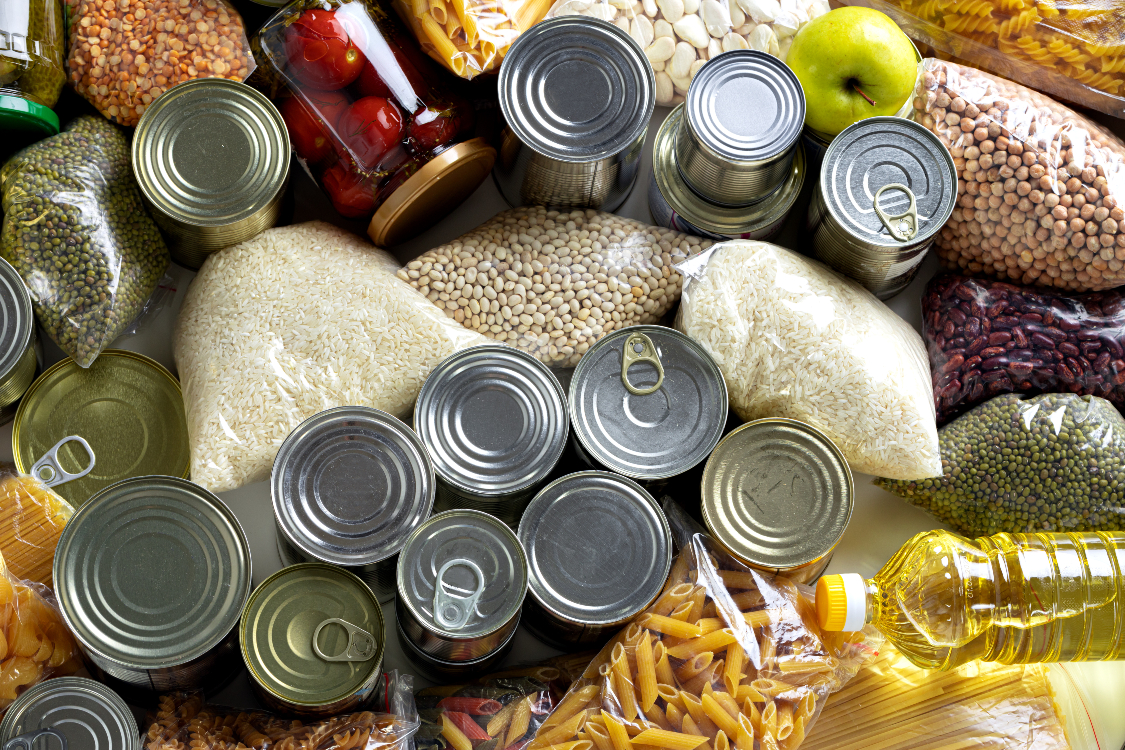 An overhead shot shows tinned and pantry staples, such as pasta, adzuki beans, chickpeas, rice, canola oil, and more.