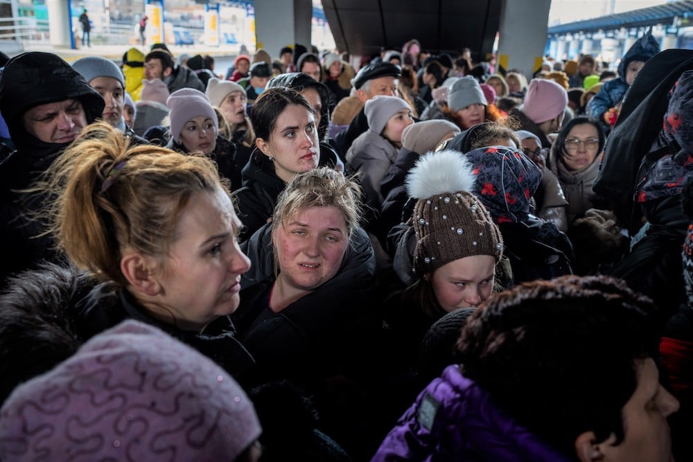 Many people crowd a train station.