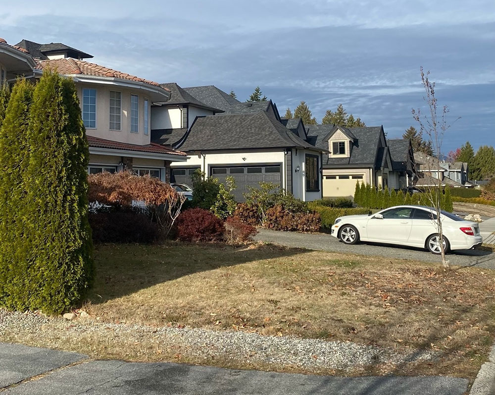 A suburban house with a white car in the driveway.