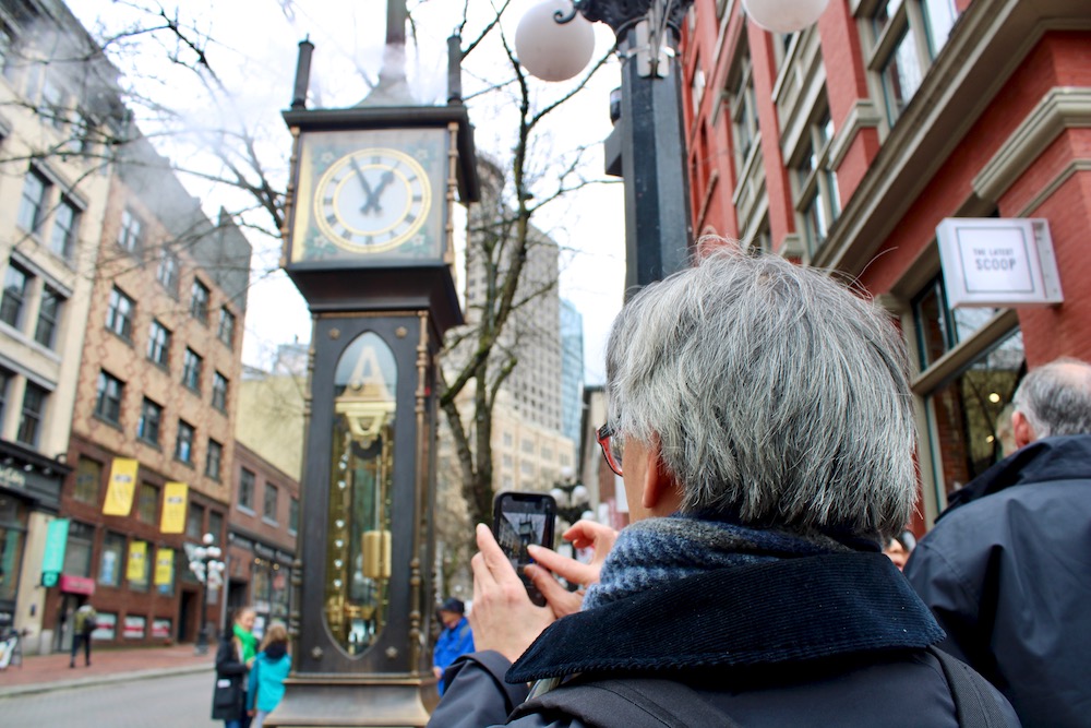 A contemporary photo shows people gathering at the steam clock.