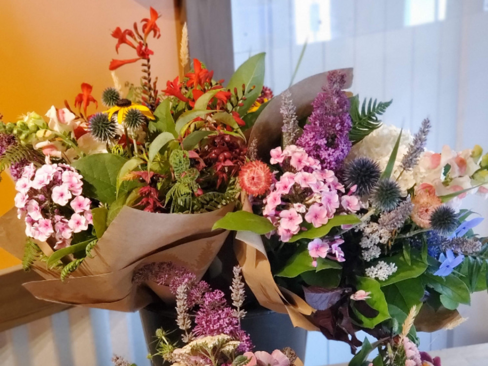 Several paper-wrapped bouquets have been placed into a bucket on a table.
