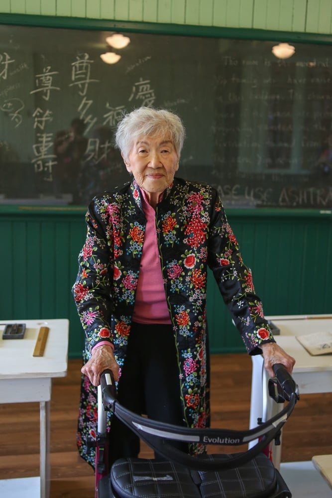 舊教室裏，一位坐在助行器上的華裔老婦人。