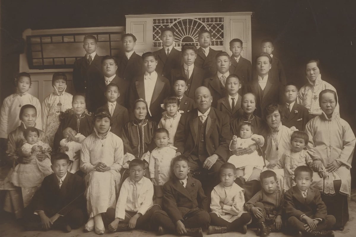 一張舊的深褐色照片，照片上是一個由孩子和妻子組成的大家庭，中間坐著一個看上去很宏偉的男人。