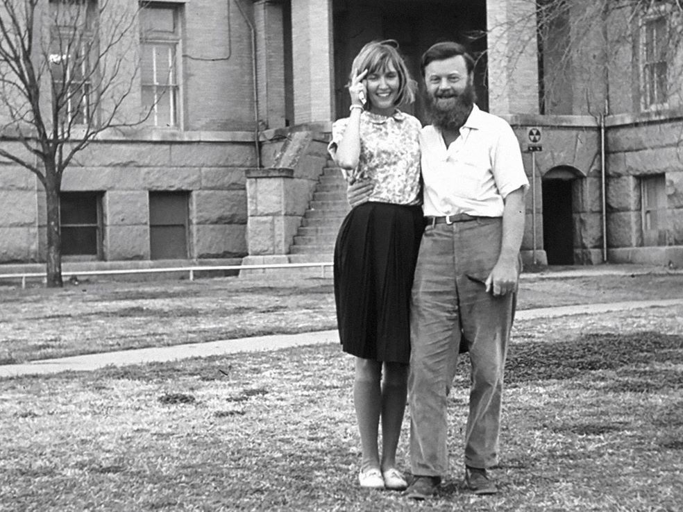 Claire Wheeler and Farley Mowat in a black and white photograph, standing close together, looking happy.