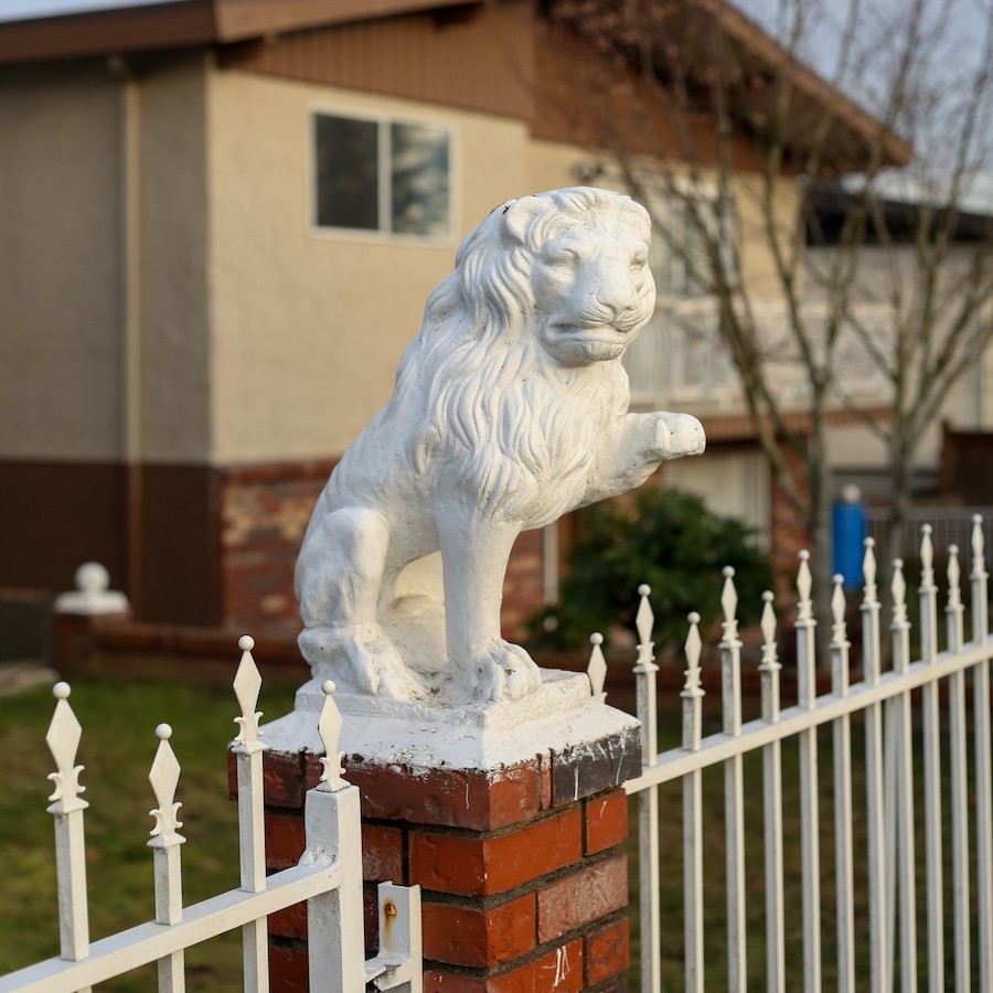 A little concrete figurine of a lion on the post of a brick fence.