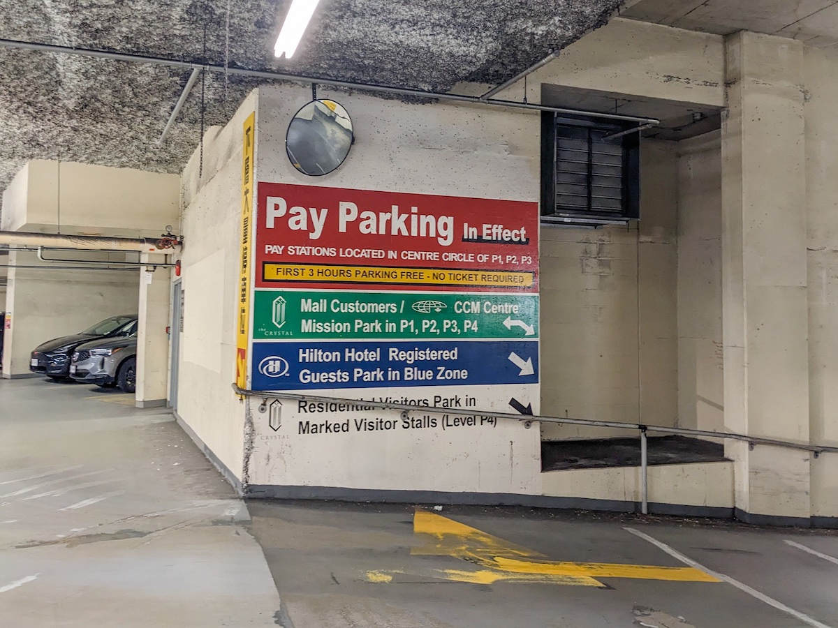 A painted sign reads 'Pay Parking in Effect.' It also lists, in a colour-coded fashion, three different zones of parking.