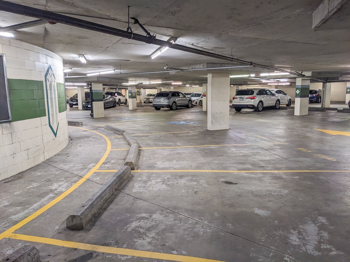 Parking spots spoke out from a circular concrete centre. Cars are parked amidst concrete pillars.
